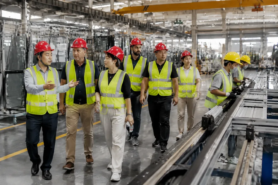International project partners touring a Foshan window and door production line in safety helmets